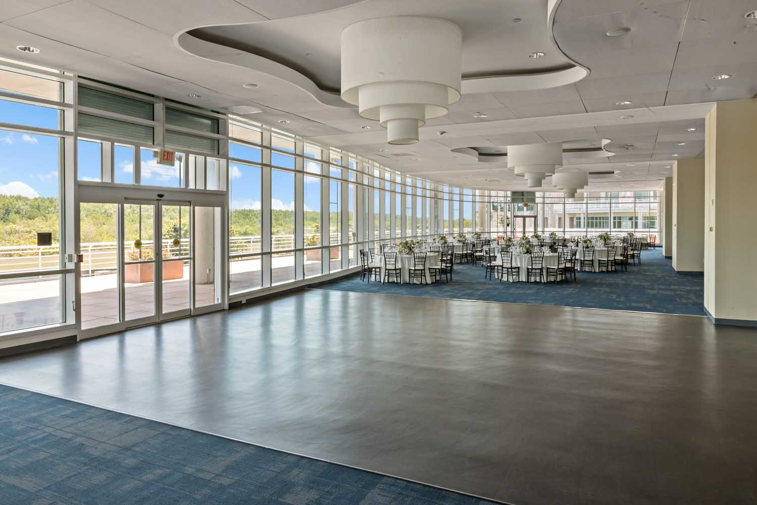 Palm Ballroom with polished dance floor, dining tables, and panoramic windows overlooking the estate grounds