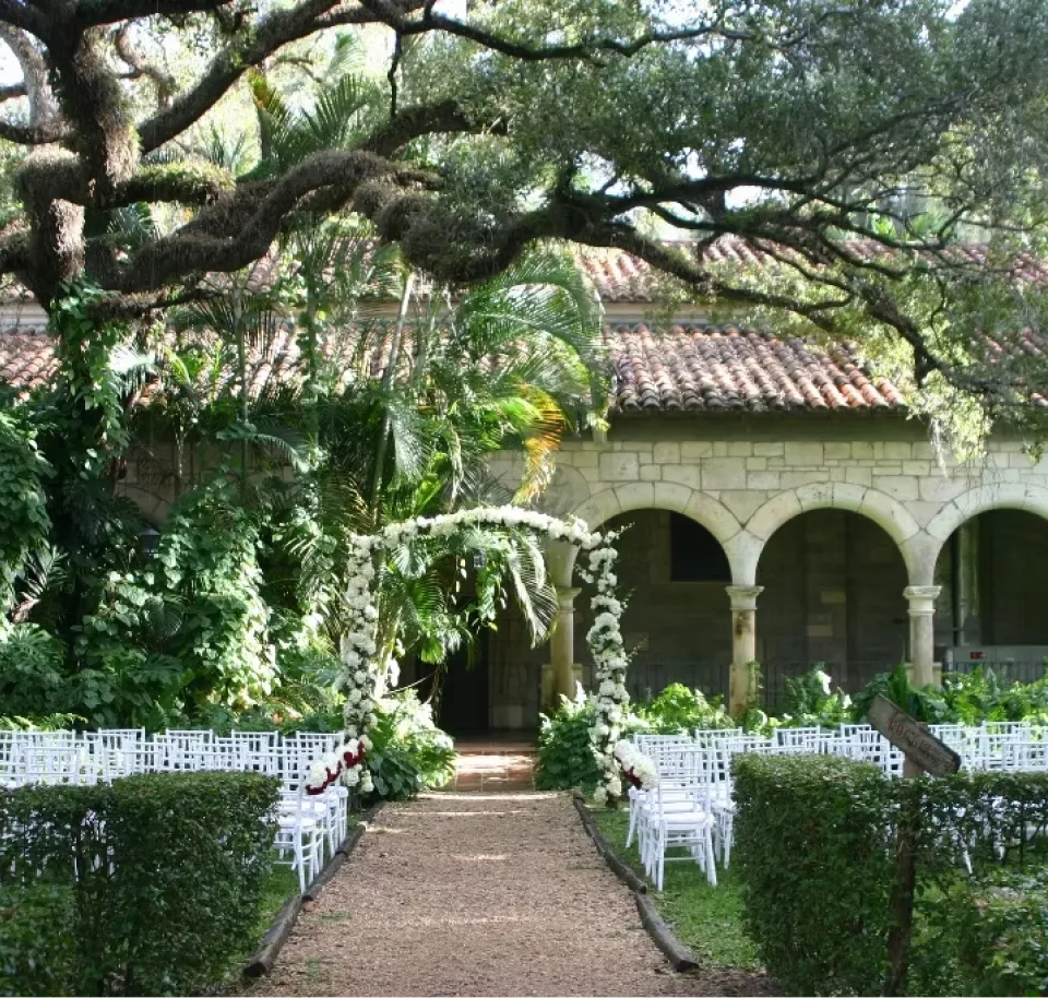 Exterior view of Coral Gables Country Club with palm trees, a golf course, and a clubhouse