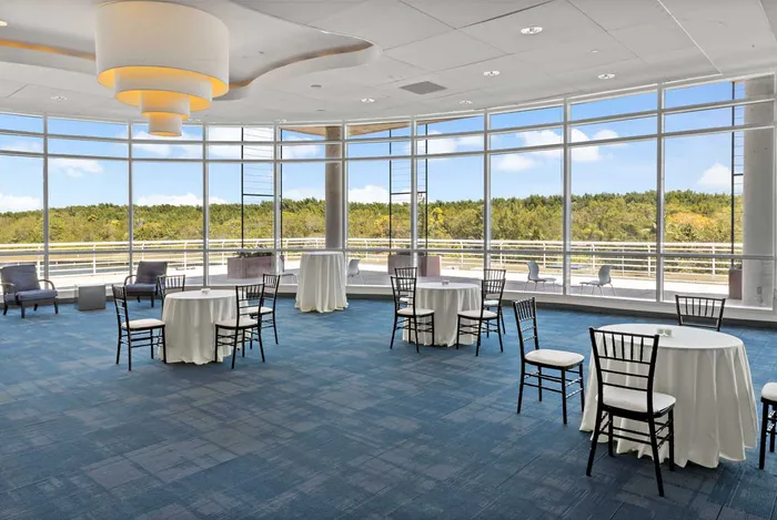 Palm Ballroom at Palmetto Bay Village Center set for a reception with round tables, white linens, and floor-to-ceiling windows overlooking tropical greenery