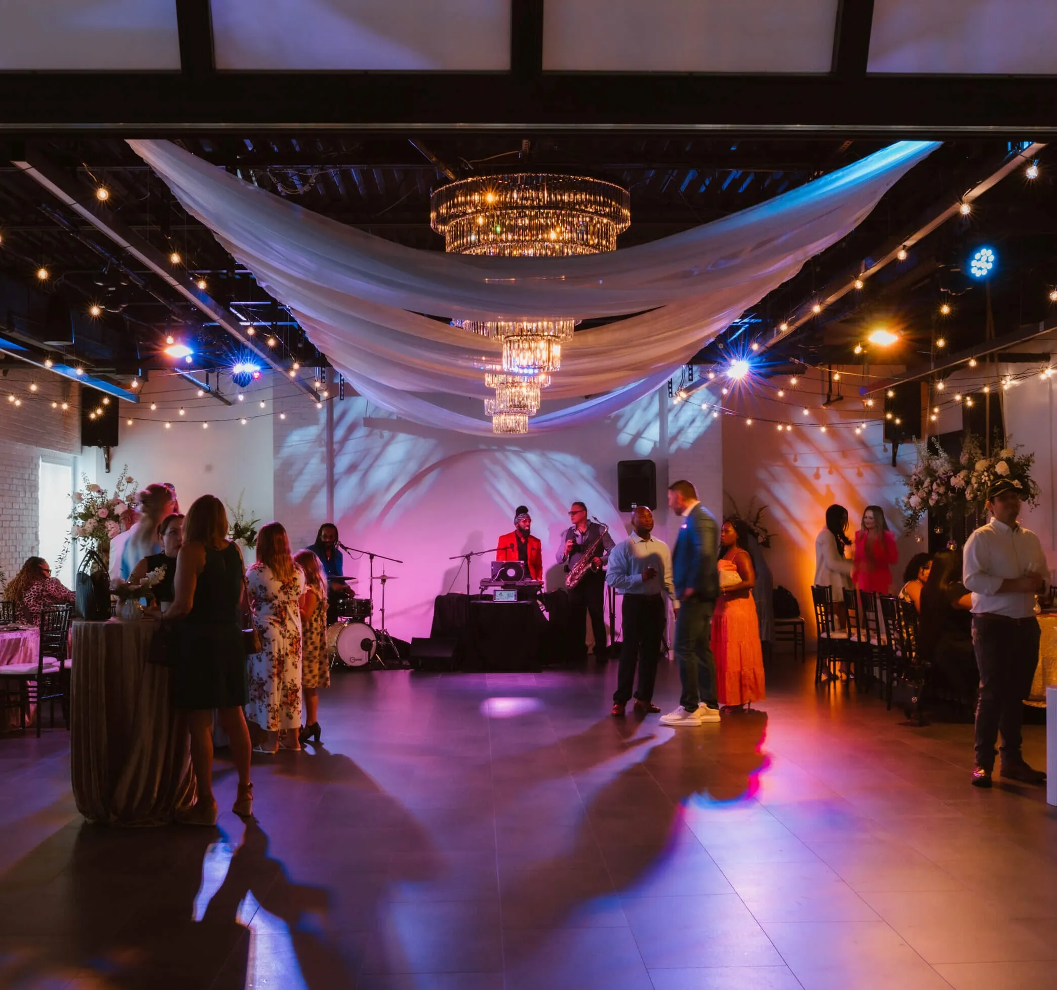 Indoor wedding reception at Trellis 925 with brick walls, draped ceilings, string lights, and elegant table decor