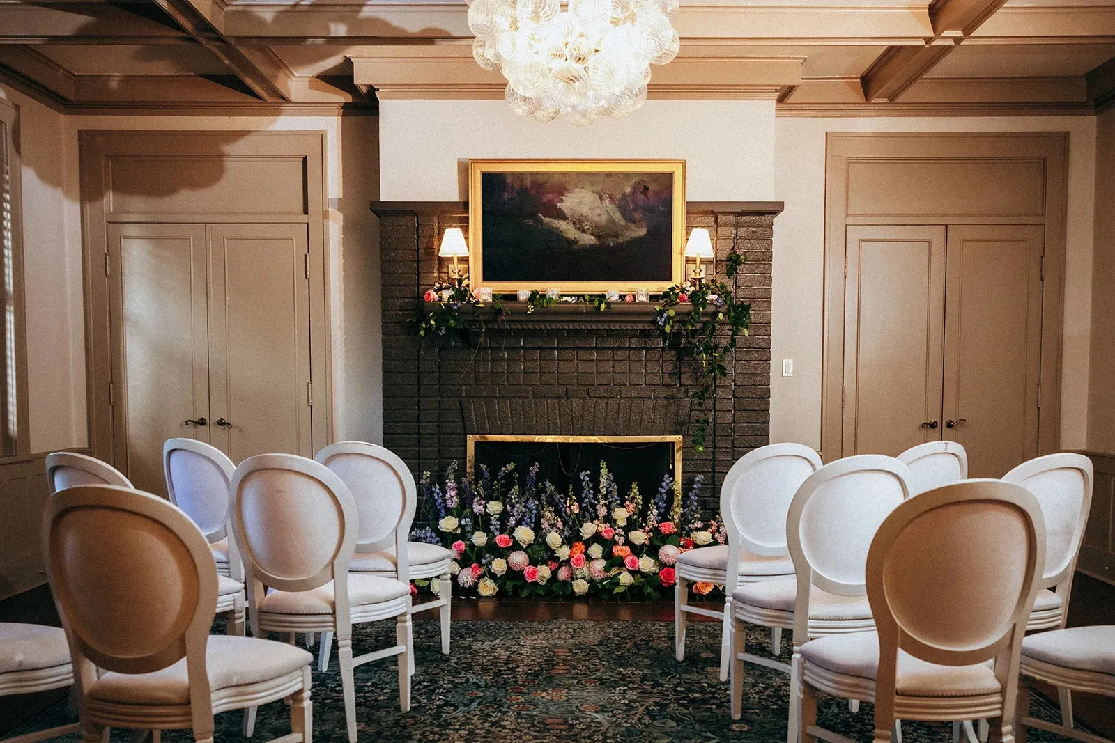 Indoor ceremony setup at The Woodruff with white chairs, floral fireplace mantel, and soft natural light