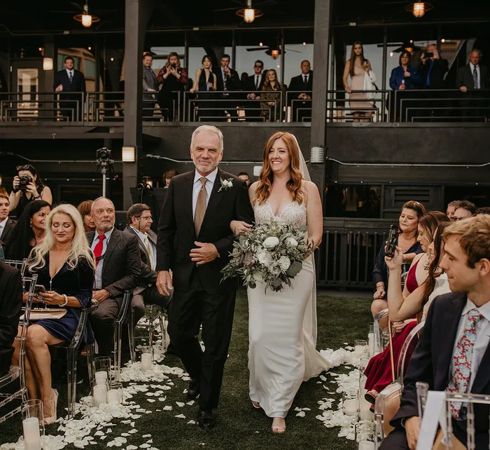 Outdoor rooftop wedding setup at Station House with clear chairs, string lights, and downtown city buildings in the background