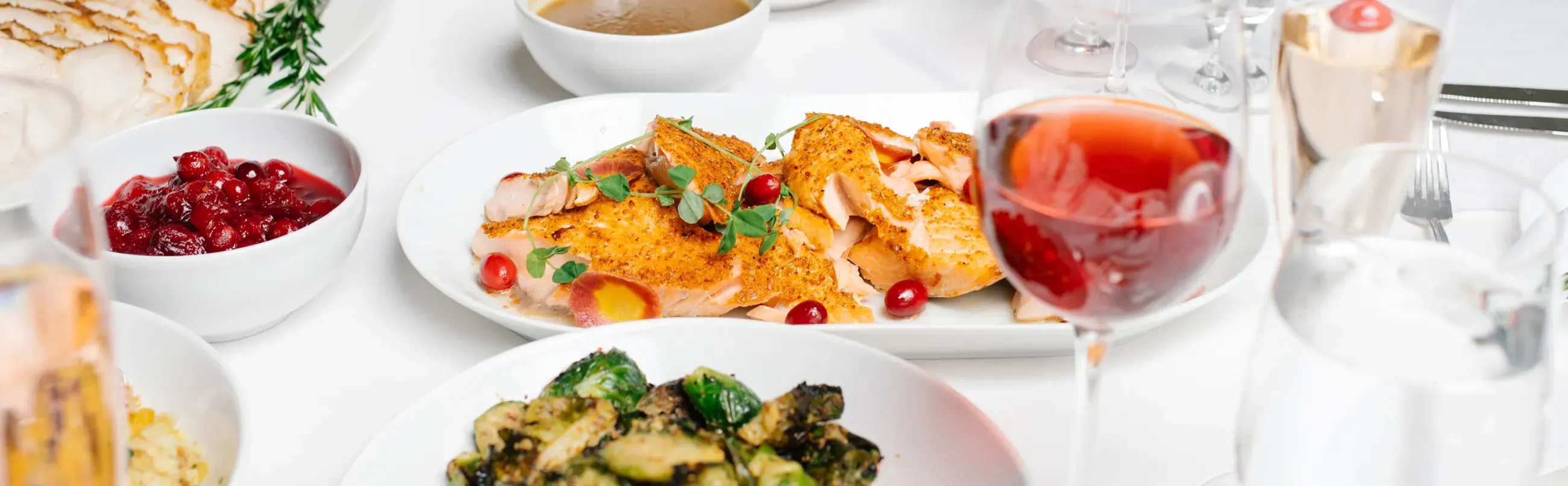 Outdoor wedding setup with long tables, elegant chairs, floral decorations, and a view of the water